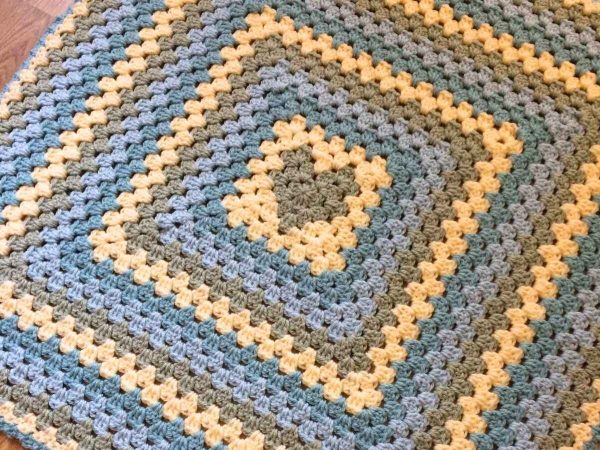 Crochet blanket with a green heart at the centre
