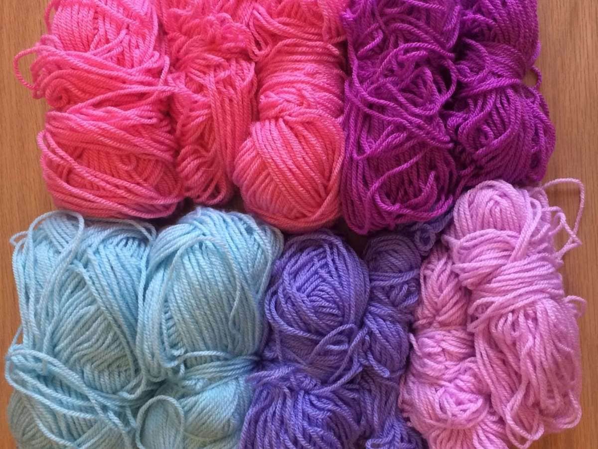 Small stash of spare yarn in pinks and purple colours ready to be used up in a crochet project
