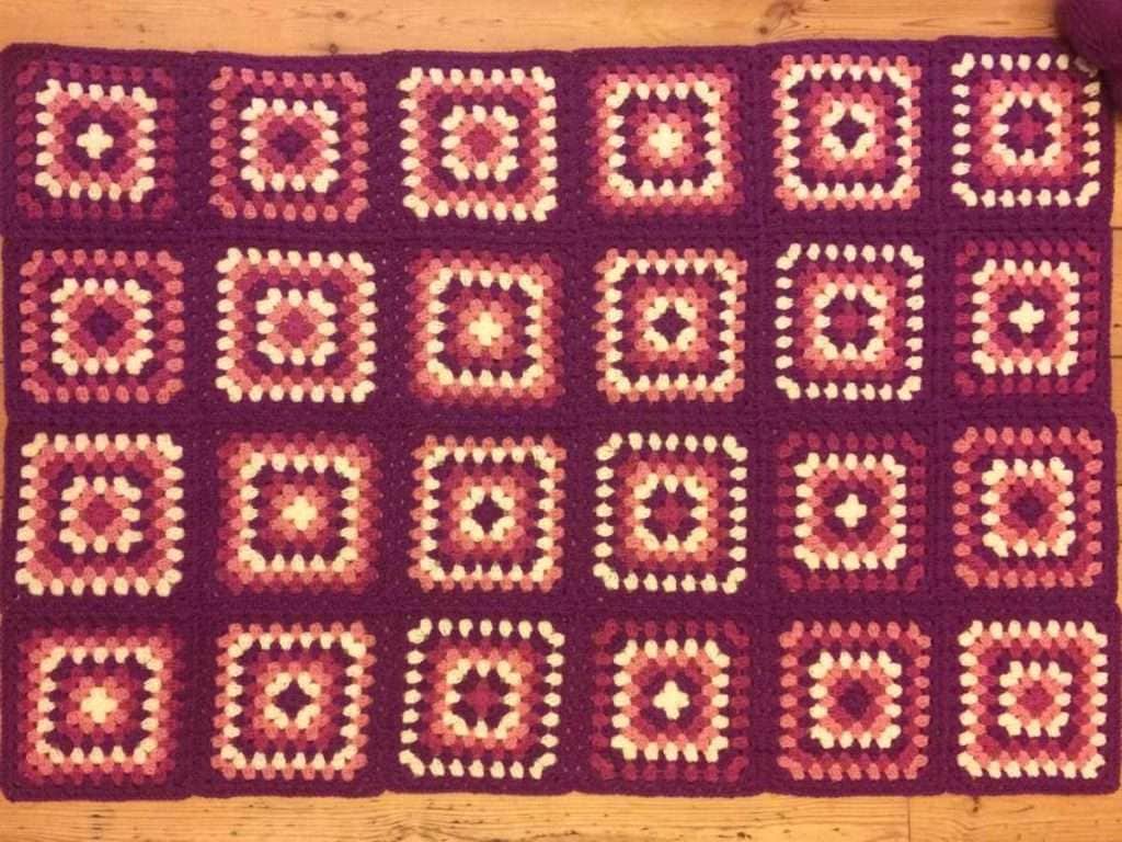 Photo of the individual Granny Squares all joined with plum coloured yarn