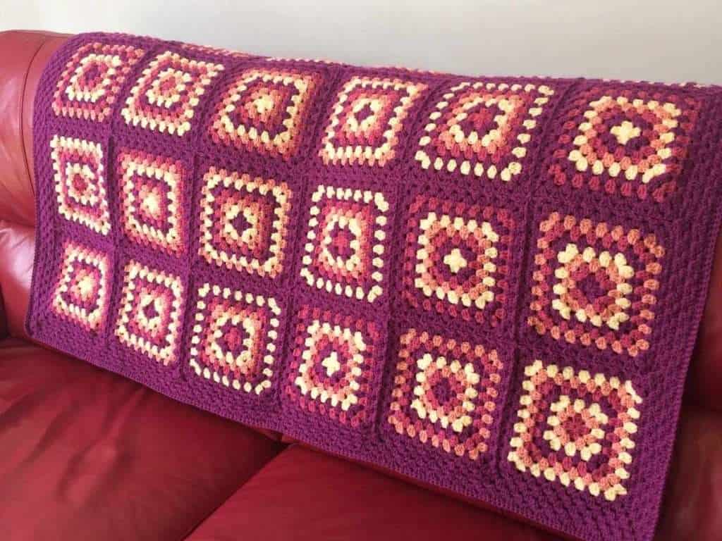 Granny Square blanket displayed on a red sofa