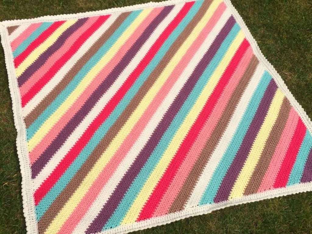 Finished corner to corner moss stitch blanket arranged on a lawn