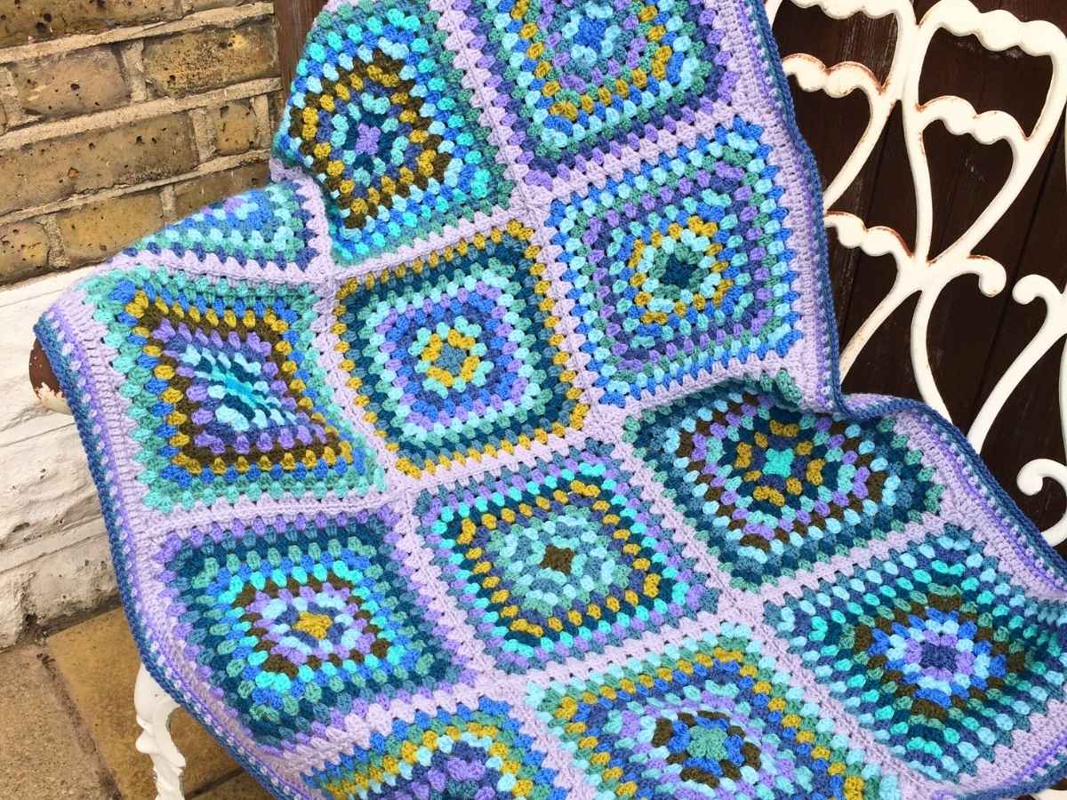 Handmade Blue Granny Square Blanket displayed on a garden bench