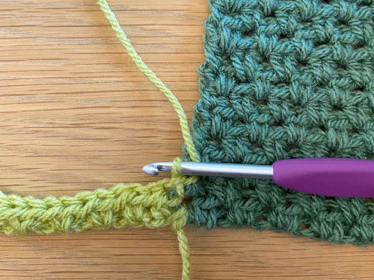Green yarn and purple crochet hook