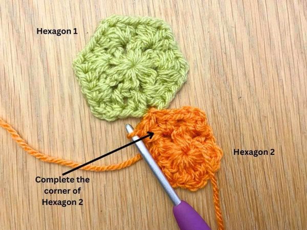Orange crochet hexagon partly joined to a green hexagon using the join-as-you-go method