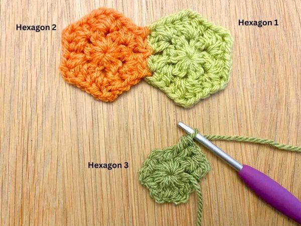 Dark green crochet hexagon being added to a light green and an orange hexagon