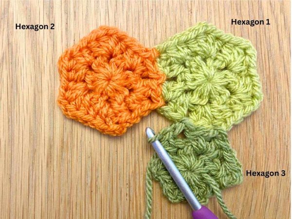 Joining a dark green crochet hexagon to two other hexagons using the join-as-you-go method