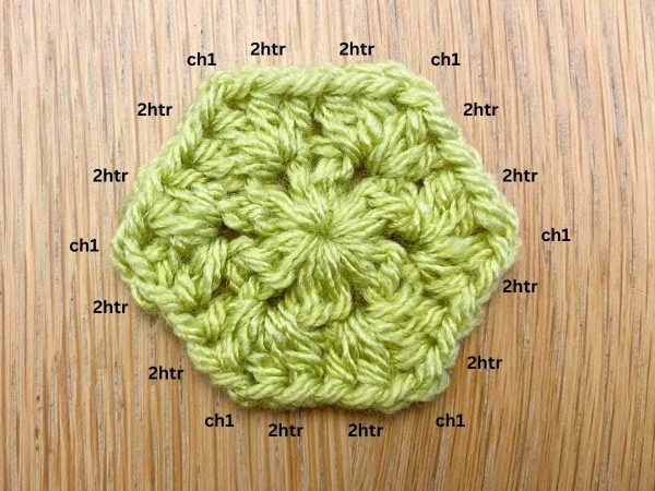 Crochet hexagon with two rounds made with green yarn.