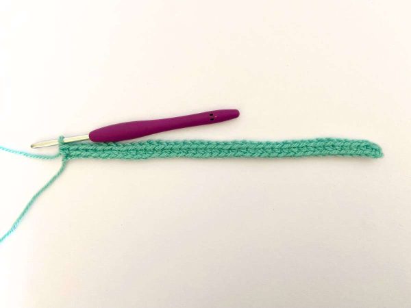Row one of the Heart Block pattern with green yarn and a purple crochet hook