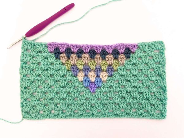 Green yarn and purple crochet hook used to indicate row 13 of the crochet pattern and showing the colour changes of the row to create a heart