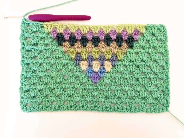 Green yarn and purple crochet hook used to indicate row 14 of the crochet pattern and showing the colour changes of the row to create a heart