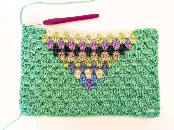 Green yarn and purple crochet hook used to indicate row 15 of the crochet pattern and showing the colour changes of the row to create a heart