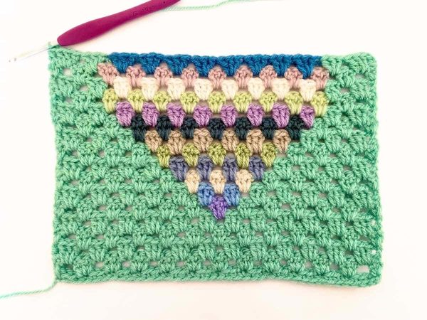 Green yarn and purple crochet hook used to indicate row 17 of the crochet pattern and showing the colour changes of the row to create a heart