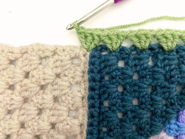 Working a crochet border with green yarn
