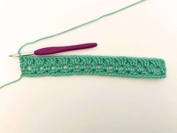 Green yarn and purple crochet hook used to indicate the third row of the crochet pattern