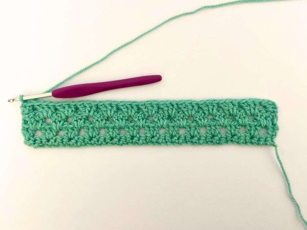 Green yarn and purple crochet hook used to indicate the fourth row of the crochet pattern