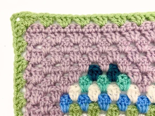Photo showing a completed first round of a crochet border around a blanket